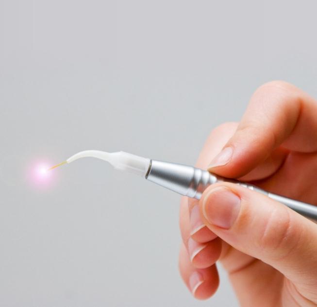 Hand holding a metal dental laser device