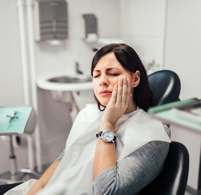 Woman holding her cheek in pain while visiting emergency dentist