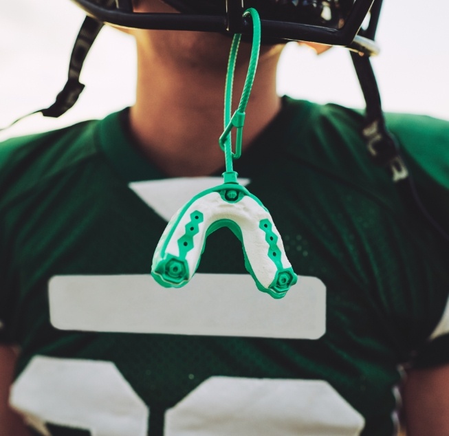Football player with an athletic mouthguard hanging from their helmet