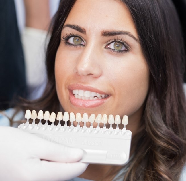 Cosmetic dentist in Hanford holding a shade guide near a smiling patient