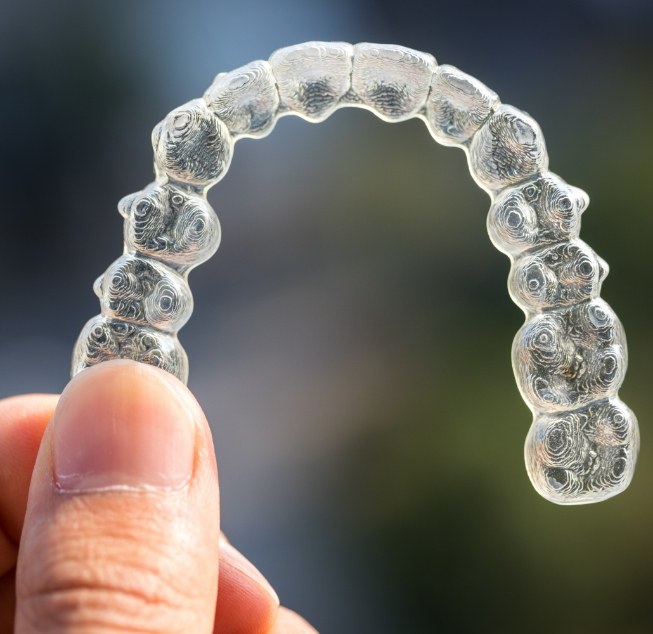 Hand holding an Invisalign clear aligner