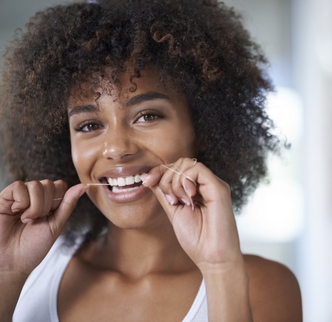 Woman smiling while flossing her teeth