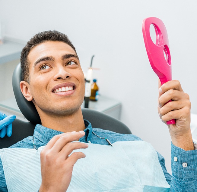 Patient smiling at dentist with pink mirror