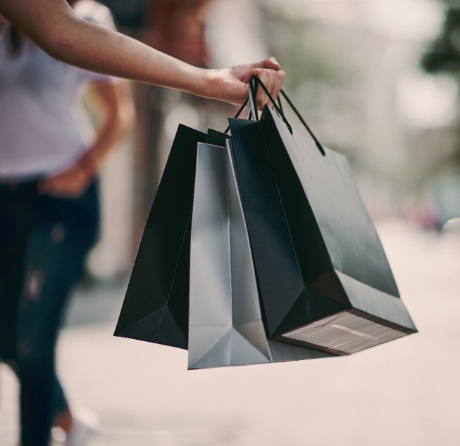 Person holding several shopping bags in one hand while walking down street